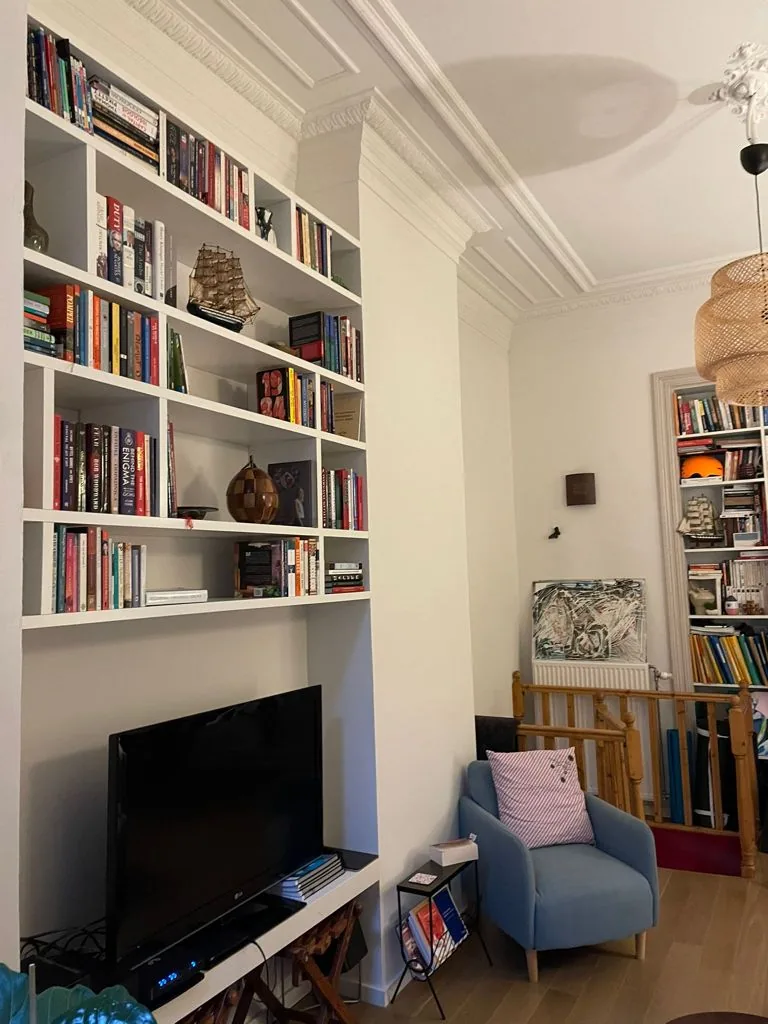 Bibliothèque suspendue blanche sur mesure dans un salon, au-dessus du téléviseur